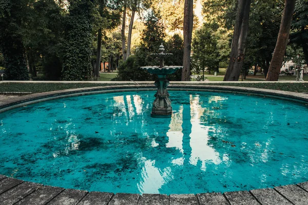 Fontana decorata e laghetto artificiale con acqua blu nel parco — Foto stock
