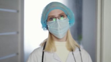 Yorgun kadın doktor ya da hastane çalışanı maskesini çıkarır.