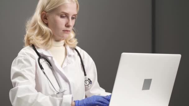Женщина-врач, работающая за компьютером, ввод данных из файла пациента. — стоковое видео
