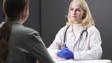 Ciddi genç bayan doktor bir kadın hastayla konuşuyor. Tıbbi geçmişi kontrol eder