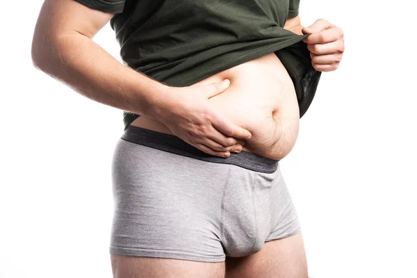 A man in a t-shirt holds a fat side — Stock Photo, Image