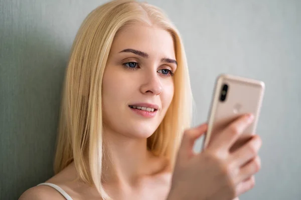 Menina loira bonito de olhos azuis assistindo vídeo no telefone — Fotografia de Stock