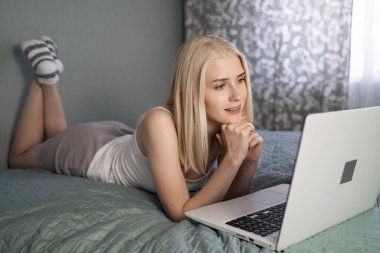 Dizüstü bilgisayar kullanan ve yatağında rahat bir şekilde seksi giyinen kadınlar..