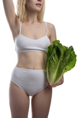 Elinde koca bir demet taze marul tutan genç bir kadın. İzole edilmiş beyaz arka plandaki kadının ellerinde yeşil salata yaprakları. Vejetaryen, vejetaryen yemeği. Boşluğu kopyala.