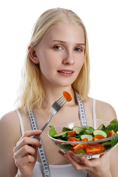 Porträt eines fröhlichen, verspielten Mädchens, das frischen Salat aus einer Schüssel isst und isoliert vor weißem Hintergrund zwinkert — Stockfoto