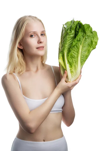 Jovem mulher segurando um monte grande de alface fresca. A salada verde parte em mãos da mulher no contexto branco isolado. Vegan, comida vegetariana. Espaço de cópia. — Fotografia de Stock