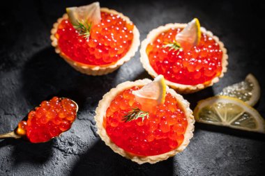 Siyah arka planda servis edilen kırmızı havyarlı turtalar. Gurme deniz ürünleri