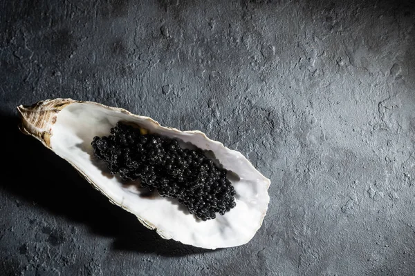 Geopende oesters met zwarte steurkaviaar zwarte betonnen ondergrond. Bovenaanzicht, flat lay, kopieerruimte. — Stockfoto