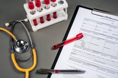 Tıp doktorları masada çalışıyor. Hasta profili ve steteskop masada. Hasta profili ve steteskop masada. Doktor hastanın kan tahlil sonuçlarını kaydediyor.