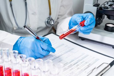Kan testi tüpleri. Üst düzey kadın bilim adamı laboratuvar DNA testinde kan test tüplerini inceliyor.