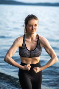 Genç ve atletik bir kız kollarının ne kadar şişkin olduğunu gösterir.