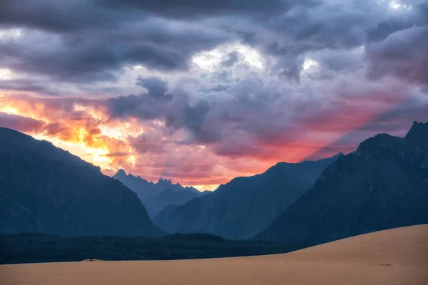 De lucht wordt verlicht door een roze zonsondergang tegen de achtergrond van de noordelijke woestijn en bergen — Stockfoto