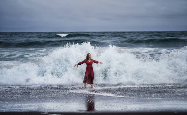 Девушка в красном платье на фоне драматических бурных волн — стоковое фото