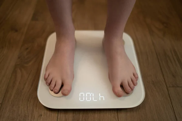 Woman measuring her weight using scales on wooden floor. — Stock Photo, Image