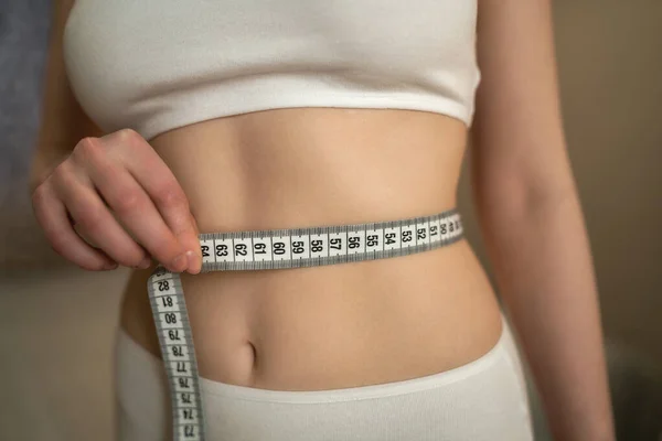 Close up photo of healthy woman with slim belly measuring her waists size — Stock Photo, Image