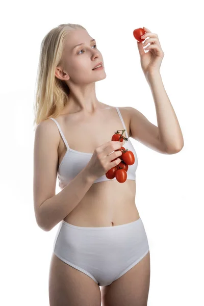 Krásná mladá žena jíst rajčata — Stock fotografie