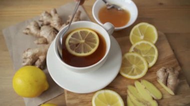 Zencefil, limon, bal, nane, çaydanlık ve bardak masada.