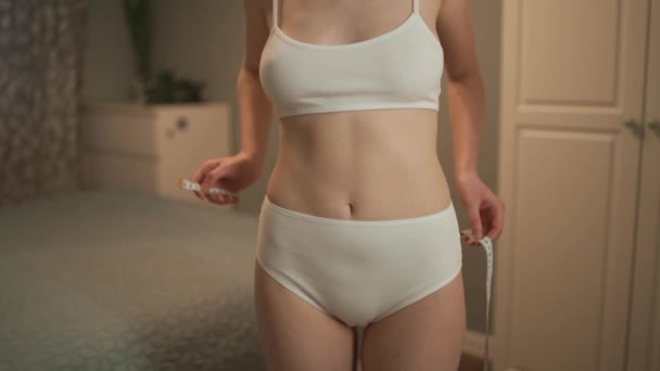 Mujer delgada joven está midiendo la cintura. — Vídeos de Stock