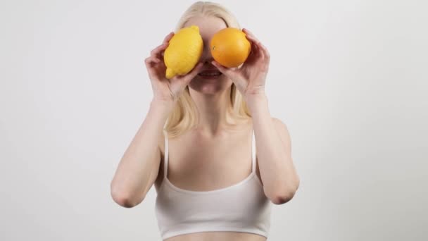 Ελκυστική γυναίκα που χορεύει με φρέσκο πορτοκάλι και λεμόνι, στην ευχάριστη θέση να περνούν χρόνο στο σπίτι — Αρχείο Βίντεο