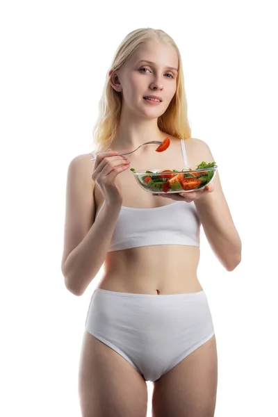 Bella donna mangiare una ciotola di insalata mentre in piedi su uno sfondo bianco — Foto Stock