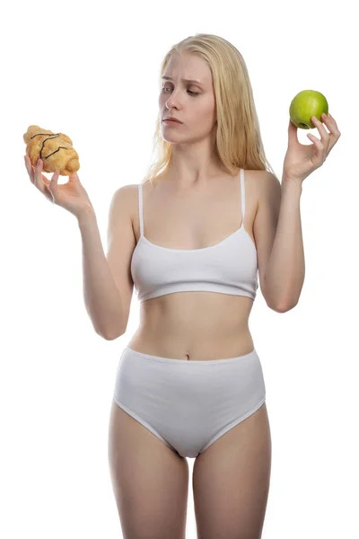 Shoked lady looks at a croissant and an apple — Stock Photo, Image