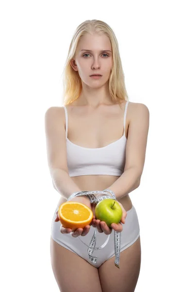 Яблуко та апельсин у жіночих руках пов'язані бірюзовою вимірювальною стрічкою, ізольовані на білому тлі — стокове фото