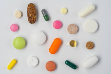 Beyaz arka planda izole edilmiş çeşitli hap, tablet ve kapsüllerin düz yatışı.
