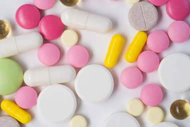 Beyaz arka planda izole edilmiş çeşitli hap, tablet ve kapsüllerin düz yatışı.