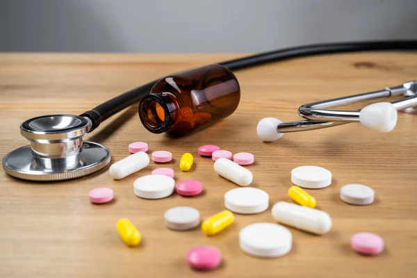グレーの木製のテーブルの上に蓄音機付きの様々な薬や錠剤。医療だ。ヘルスケアと薬局. — ストック写真
