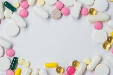 Beyaz arka planda çeşitli renkli haplar ve kapsüller