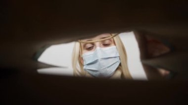 Genç bayan internet mağazasından gelen kutuyu dikkatlice açıyor. Coronavirus salgını karantinası