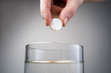 Cam şeffaf bir bardağa atılan köpüklü tablet, cam masanın üzerinde.