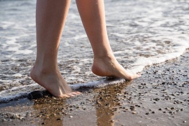 Sörfler üzerlerini yıkarken kumun üzerinde iki ayak. Sıcak filtre uygulandı