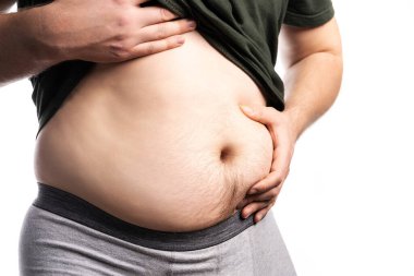 Olgun adam göbeğini tutar ve ağırlığını fotokopi aletiyle beyaz arka plana karşı değerlendirir..