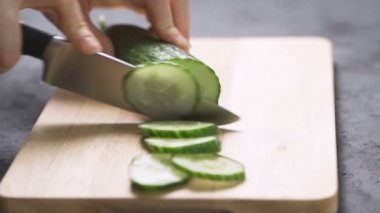 Salatalık doğrayan kadın. Kadın elleri yeşil salatalık halkalarını kesti..