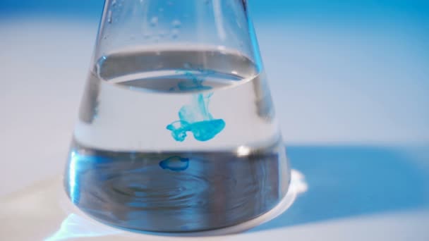 No laboratório, um cientista realiza uma experiência química. Despeje o líquido azul no frasco. Conceito - investigação bioquímica, experiências genéticas — Vídeo de Stock