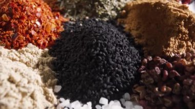 Bitki yığınları baharat tozları doğal ve sağlıklı kokulu kokulu tohumlar, tohumlar beyaz masada birbirinden ayrı yatar. Dolly çekim yapar Kamera baharatlar arasında hareket eder