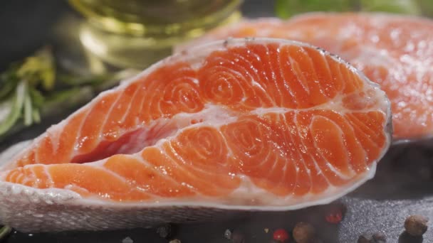 Salmone. Bistecca di pesce rosso di trota cruda con erbe aromatiche e limone e olio d'oliva ruotato su ardesia. — Video Stock