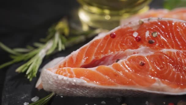 Salmone. Bistecca di pesce rosso di trota cruda con erbe aromatiche e limone e olio d'oliva su ardesia. — Video Stock