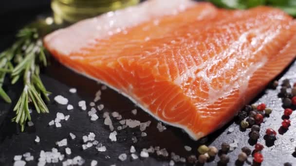 Salmone. Bistecca di pesce rosso di trota cruda con erbe aromatiche e limone e olio d'oliva ruotato su ardesia. — Video Stock