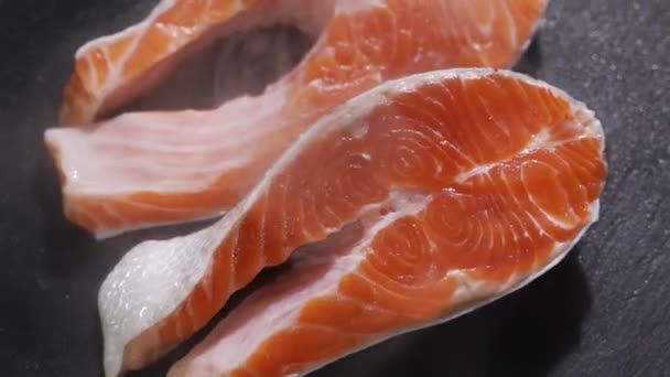 Preparación de filete de salmón. Especias y sal espolvoreadas sobre un trozo de salmón crudo. — Vídeos de Stock
