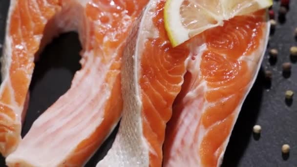 Salmón. Filete de pescado rojo de trucha cruda con hierbas y aceite de limón y oliva rotado sobre pizarra. — Vídeos de Stock
