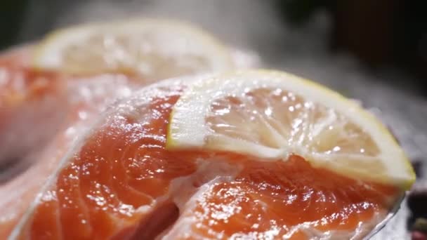 Лосось. Сырой форель Red Fish стейк с травами и лимоном и оливковым маслом вращается на шифер. Медленное движение 4K UHD видео — стоковое видео