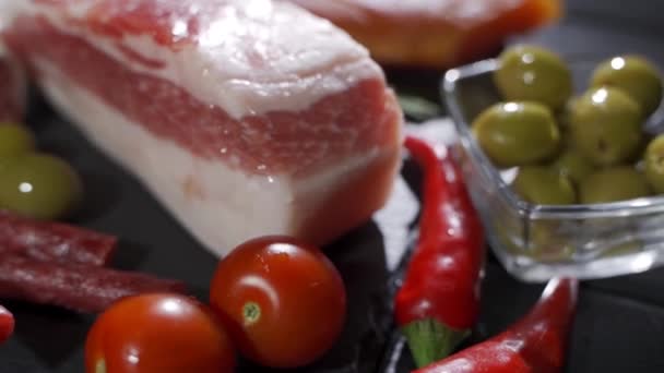 Surtido de embutidos, jamón, salami, tocino y tomates en la bandeja de piedra negra — Vídeos de Stock
