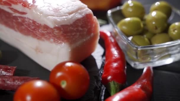 Charcuterie, jambon, salami, bacon et tomates sur le plateau en pierre noire — Video