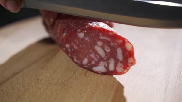 Hand expert snijdt Parma gekruide salami, dun gesneden met een mes en straalt de smaak en de Italiaanse smaak — Stockvideo