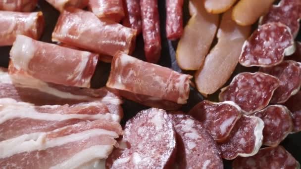 Geassorteerde delicatessen, ham, salami, spek en tomaten op het zwarte stenen dienblad — Stockvideo