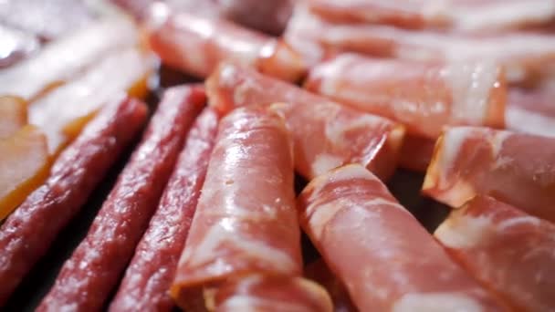 Blandat delikatesskött, skinka, salami, bacon och tomater på den svarta stenbrickan — Stockvideo