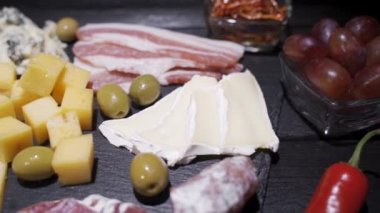 Dilimlenmiş salam, kraker, yeşil zeytin, fındık ve böğürtlen ve çeşitli peynirle kesme tahtası.