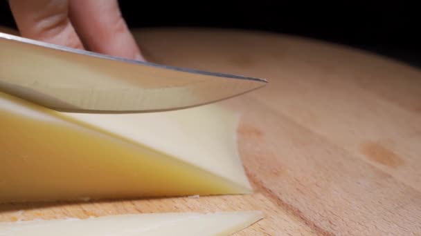 Composición de queso italiano, sobre una tabla de cortar de madera. Una mano toma el cuchillo y rompe un par de piezas para saborear la calidad. — Vídeos de Stock